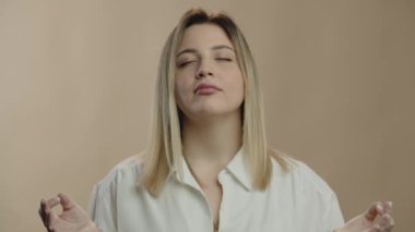 Blonde woman trying to calm down. Beautiful girl inhales and exhales with closed eyes to pull herself together. Zen concept. High quality 4k footage