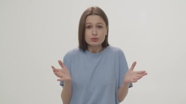 The excited woman crosses her fingers and smiles to see that her predictions came true. Beautiful brunette makes a wish. Studio shooting against a white wall. High quality 4k footage