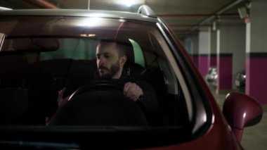 Bearded driver reading phone message and showing yes gesture. Brunette man in the car received good news Happy guy using his smartphone at the parking lot. High quality 4k footage