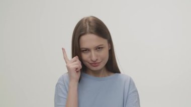 A brown-eyed brunette taps her temple with her finger and points directly at the camera. Portrait sketch of a brown-eyed woman on a white background. High quality 4k footage