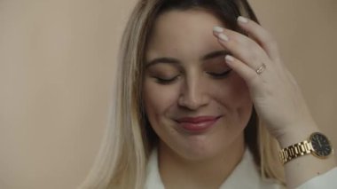 Smiling woman with golden wristwatch touching her hair. Close-up portrait of beautiful blonde girl posing with smile. High quality 4k footage