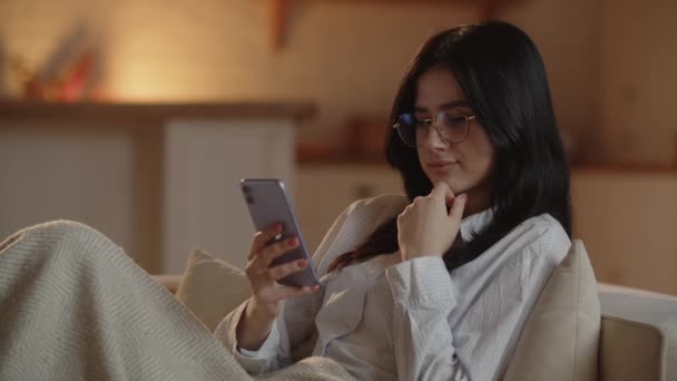 Pensive Girl Glasses Using Smartphone While Chilling Couch Young Woman — Stockvideo