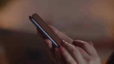 A woman scrolls through the news feed on her smartphone. Female hands hold a black smartphone. Phone user swiping the screen. High quality 4k footage