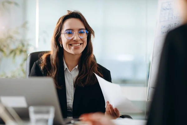 Smiling female supervisor discussing report with employee. Selective focus of happy ceo woman talking to coworker in office. High quality photo