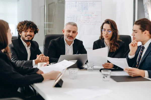Group of businesspeople reading business report. Office managers doing paperwork during conference. Confident executive having meeting with his employees. High quality photo