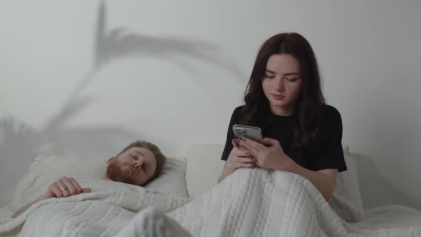 Een Jonge Vrouw Sms Terwijl Haar Man Slaapt Mooi Meisje — Stockvideo