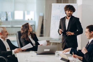 Businesspeople analyzing new company strategy in the meeting room. Group of businessmen discussing report during conference. Young manager doing presentation to the executive team. High quality photo
