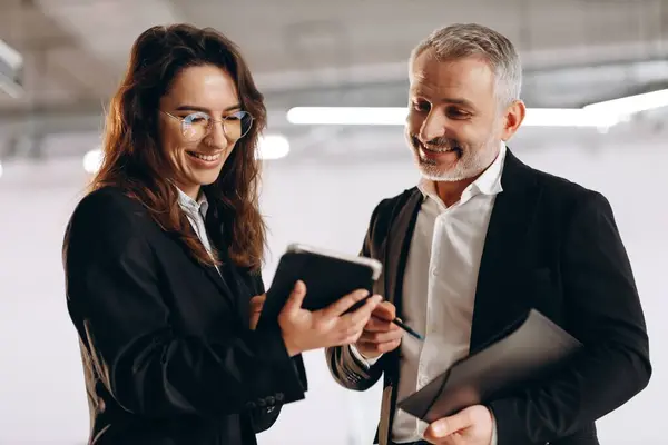 Smiling woman showing digital tablet to her boss. Indoor shot of happy businesspeople with digital device in office. Business technologies. High quality photo