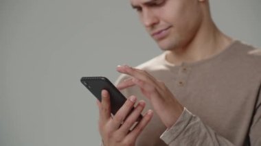 Cropped view of a man browsing news on a smartphone. A man taps on the smartphone screen, scrolls the social network feed. High quality 4k footage
