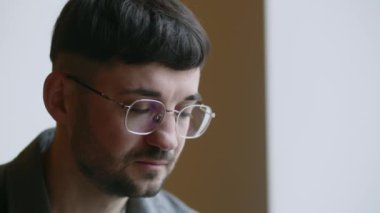 Businessman starts laughing during a telephone conversation. Discussing work tasks over the phone. Young man in glasses answering call with smile. High quality 4k footage