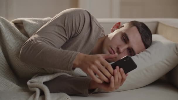 Молодой Человек Лежащий Диване Ставит Будильник Телефон Засыпает Мужчина Решил — стоковое видео