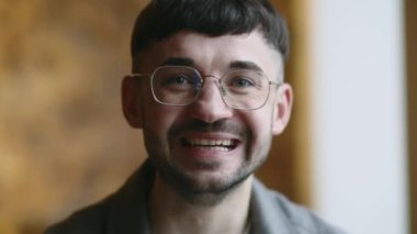 Genç adam kameraya bakarken gülümsemeye başlar. Kahkaha atan gözlüklü esmer adam. Neşeli sakallı adamın olumlu duygularını ön planda tutması. Yüksek kalite 4k görüntü