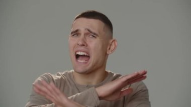 A young man looking at the camera explains something in a rude manner and waves his arms. Close-up shot of a young man who says something offensive. High quality 4k footage