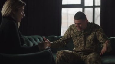 A Ukrainian soldier at the reception of a military psychologist. A female psychologist listens to a Ukrainian soldier who rudely shares his feelings after the military operations he experienced. High