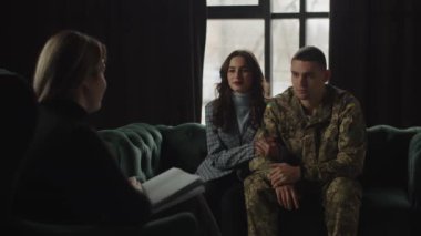 A member of the armed forces of Ukraine, sitting next to his wife holding his hand, communicates with a psychologist. A military psychologist notes an improvement in the condition of a soldier who has