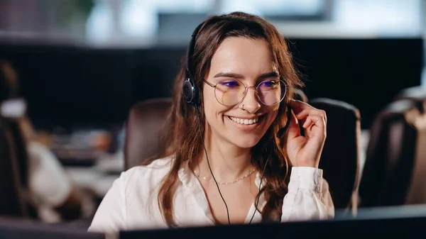 漂亮的电话经理与客户交谈 穿着眼镜在办公室工作的笑热线操作员 布鲁内特的女孩在呼叫中心工作高质量的照片 — 图库照片