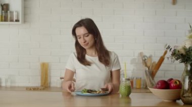 Lezzetli ve sağlıklı kahvaltı kavramı. Bir kadın bir dilim ekmekle birlikte sebze salatası yer ve salatalık suyu içer. Yüksek kalite 4k görüntü