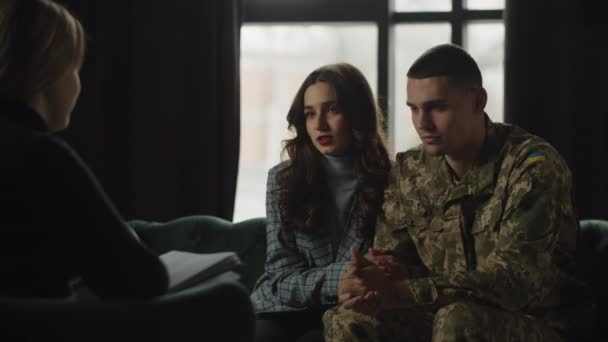 ウクライナの兵士は 彼の手を握っている妻と心理学のセッションに座っています 女性は心理学者の任命でPtsdに苦しんでいる夫をサポートしています 高品質4K映像 — ストック動画