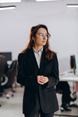 Gözlüklü şık bir iş kadını başka tarafa bakıyor. Düşünceli kadın ofis çalışanının takım elbise giymiş kapalı çekimleri. Resmi giyinmiş bir kadın girişimci. Yüksek kalite fotoğraf