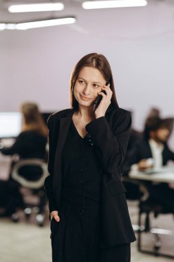 Çekici bir iş kadını telefonda konuşuyor. Ofiste akıllı telefon kullanan genç bir girişimcinin kapalı mekândaki fotoğrafı. Güzel iş kadını birini arıyor. Yüksek kalite fotoğraf