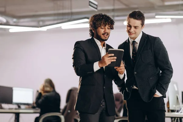 事務所でタブレットを使ってる2人の若者 デジタルガジェットでビジネスマンを笑顔 同僚は一緒に休憩をとる 高品質の写真 — ストック写真