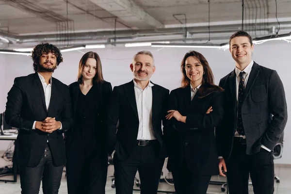 İş adamlarından oluşan bir takım kendine güvenen bir duruşta duruyor. Ofiste gülümseyen hırslı iş uzmanları. Kariyer gelişimi, girişim sahipleri. Yüksek kalite fotoğraf