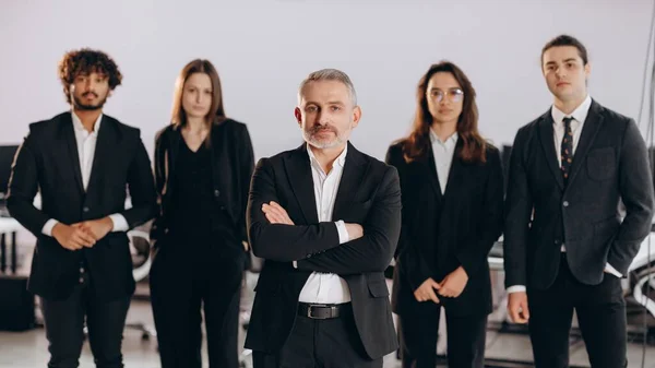Confident business owner and his employees. Group of businesspeople in black formal wear. Multicultural business team posing in office. High quality photo