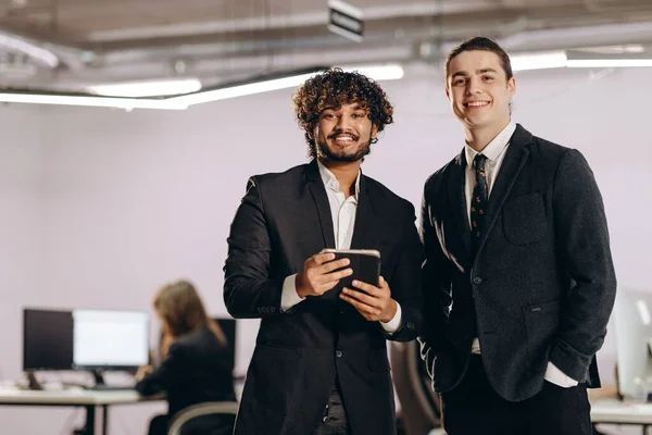 デジタル機器を持つ2人の若いビジネスマン タブレットで笑顔のオフィスマネージャーの屋内ショット 高品質の写真 — ストック写真