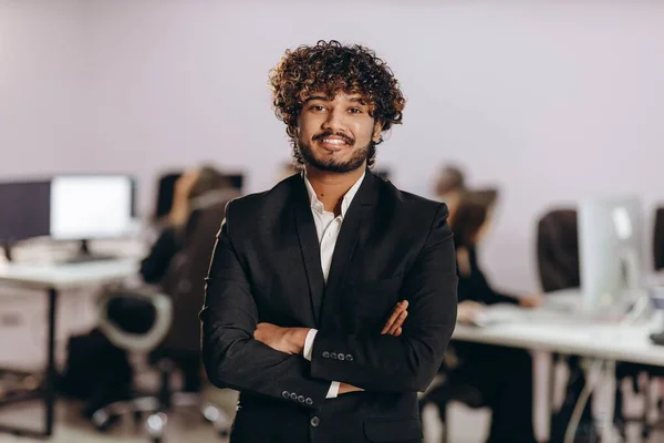 stock image Excited entrepreneur standing in confident pose in office. Happy businessman posing with crossed arms and looking at camera. High quality photo