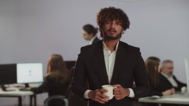 Ofisin arka planında duran takım elbiseli yorgun bir gencin videosu. Ofisteki yorucu bir günün ardından yorgun bir genci görmek. Yüksek kalite 4k görüntü