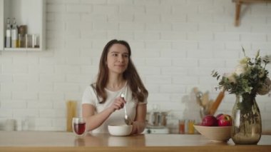 Uzun saçlı bir kadın kahvaltı masasına oturur. Esmer, kahvaltıda yulaf ezmesi ve çay içer. Yüksek kalite 4k görüntü