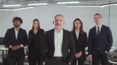 Bir danışmanlık şirketinin müdürü çalışanlarının yanındadır. Takım elbiseli insanlar ofisin arka planında poz veriyorlar. Yüksek kalite 4k görüntü