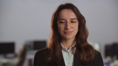 Gözlüklü ve takım elbiseli gülümseyen iş kadını manzarası. Bulanık ofis geçmişi olan bir iş kadınının yakın plan fotoğrafı. Yüksek kalite 4k görüntü