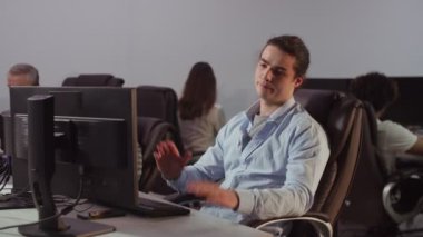 İş yerinde çalışan ve bilgisayarında sorun yaşayan genç bir adamın videosu. Adamın kafası, iş sırasında bilgisayarın çalışmayı bırakmasından dolayı karışık. Yüksek kalite 4k görüntü