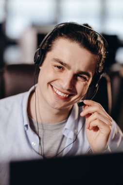 Kulaklıklı gülümseyen pazarlamacı müşterilere danışıyor. Müşteri destek asistanının portresi. Kulaklık takmış çağrı merkezi operatörü bulanık arka planda. Yüksek kalite fotoğraf