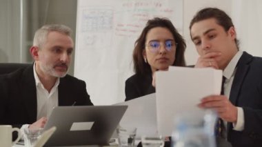 İş adamları sözleşme detaylarını tartışıyor. Ofisteki bir toplantıda evrak okuyan bir iş adamı ekibi. İş ortakları anlaşma konusunda tartışıyor. Yüksek kalite 4k görüntü