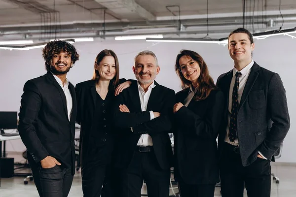 Diverse business team in black costumes. Indoor shot of business partners looking at camera with smile. Business opportunities, career growth. High quality photo