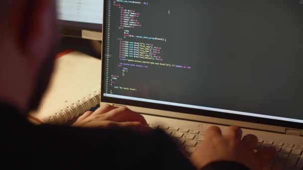 経験豊富なウェブ開発者がウェブサイト用のコードを書きます 男性プログラマーがオフィスのノートパソコンで作業しています 後ろから見る 高品質4K映像 — ストック動画