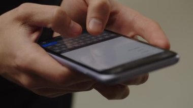 Ekranda akıllı telefon kullanıcısının görüntüsü kesilmiş. Erkek eller akıllı telefondan mesaj yazıyorlar. Bir adam telefonuna notlar yazıyor. Yüksek kalite 4k görüntü