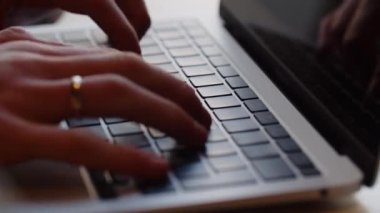 Yüzük parmağında yüzük olan bir adam bir bilgisayar klavyesinde yazıyor. Erkek ellerinin dizüstü bilgisayarda klavyeyle yazışlarını yakından çek. Yüksek kalite 4k görüntü