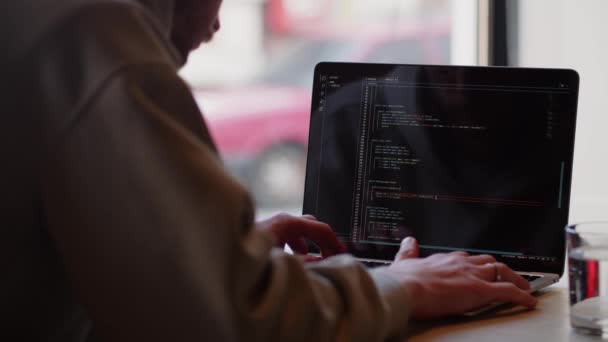 フリーランスのプログラマーはカフェに座っている間にコンピュータで動作します 男性開発者がウェブサイトのコードを書きます 後ろから見る 高品質4K映像 — ストック動画