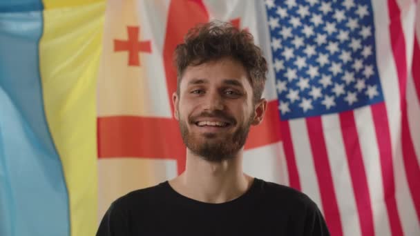 Hombre Rizado Sonriente Levanta Fondo Las Banderas Ucrania Georgia América — Vídeos de Stock