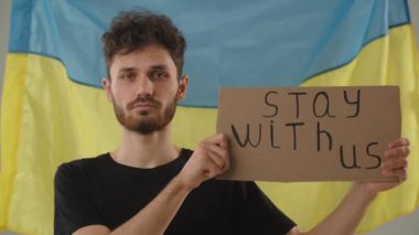 Ukraynalı adam politik gösteri yapıyor. Ukraynalı vatansever destek istiyor. Adam Ukrayna bayrağının önünde duruyor. Ukrayna kavramını destekleyin. Yüksek kalite 4k görüntü