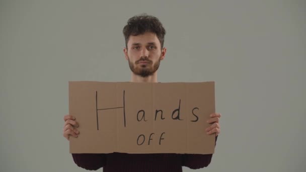 一个手拿着手拿开标语牌的示威者的前视图 一个年轻人反对侵略和战争 留胡子的家伙拿着标语牌抗议 高质量的4K镜头 — 图库视频影像