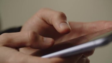 Bir adam parmaklarını akıllı telefon ekranından tıklatıyor. Akıllı telefon kullanıcısı kurye aracılığıyla biriyle sohbet ediyor. Kahverengi arka planda telefon kullanan bir adamın kısmi görüntüsü. Yüksek kalite 4k görüntü