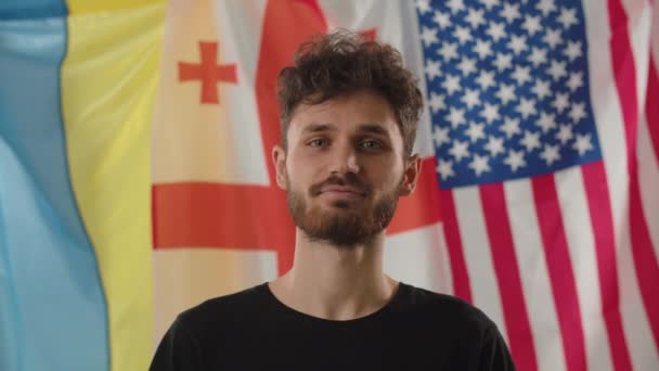 Весела Людина Стоїть Перед Українськими Грузинськими Американськими Прапорами Міжнародне Співробітництво — стокове відео