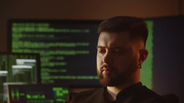 背景にコンピュータ画面でポーズをとる髭のプログラマー ハッカーが暗号を解読してる ソフトウェア開発者はオフィスでコーディングしています インターネットセキュリティ 高品質4K映像 — ストック動画