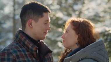 Romantik çift kış parkında eğleniyor. Genç adam ve kadın karlı ormanda birbirlerine sevgiyle bakıyorlar. Yüksek kalite 4k görüntü