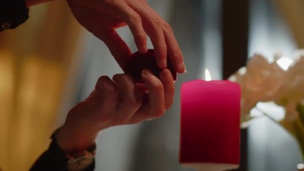 在燃烧的蜡烛的背景下 男性手牵着一个装有结婚戒指的盒子的特写镜头 一个男人提出求婚 高质量的4K镜头 — 图库视频影像