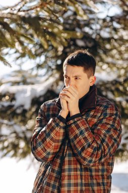 Kış ormanındaki bir esmer onları ısıtmak için ellerine üflüyor. Karlı bir parkta uzun bir sabah yürüyüşünden sonra bir adam soğuk ellerini ısıtmaya çalışır. Yüksek kalite fotoğraf